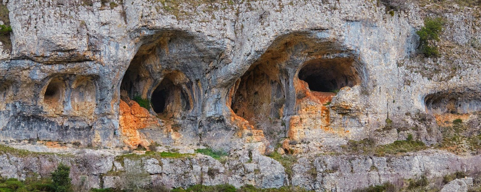 A gallery mouth in the cliff below the town, low raking sun